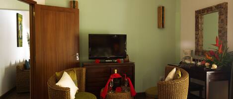 Una sala de estar con muebles de mimbre, un televisor y un espejo.