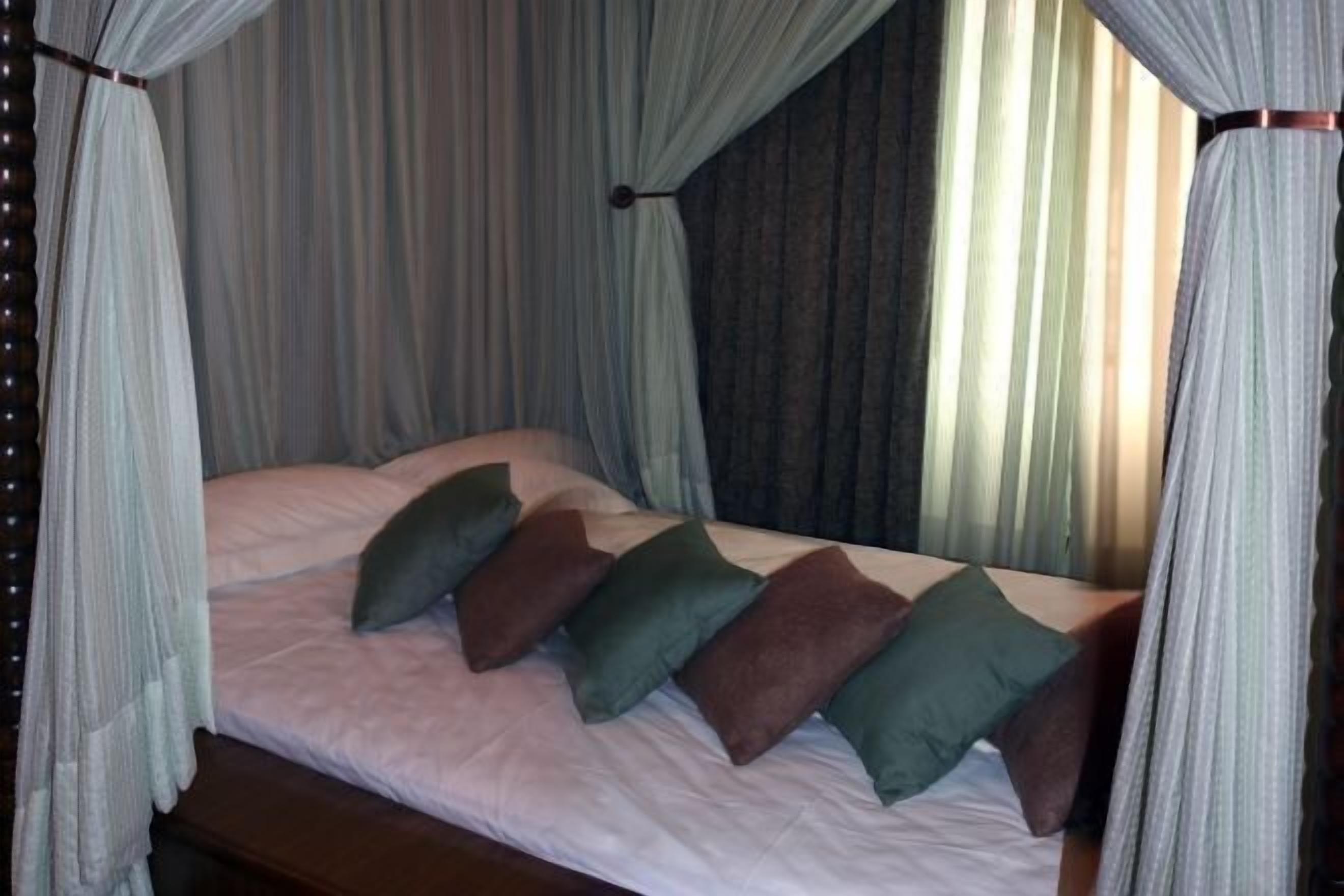 A bed with a canopy, pillows, and curtains.