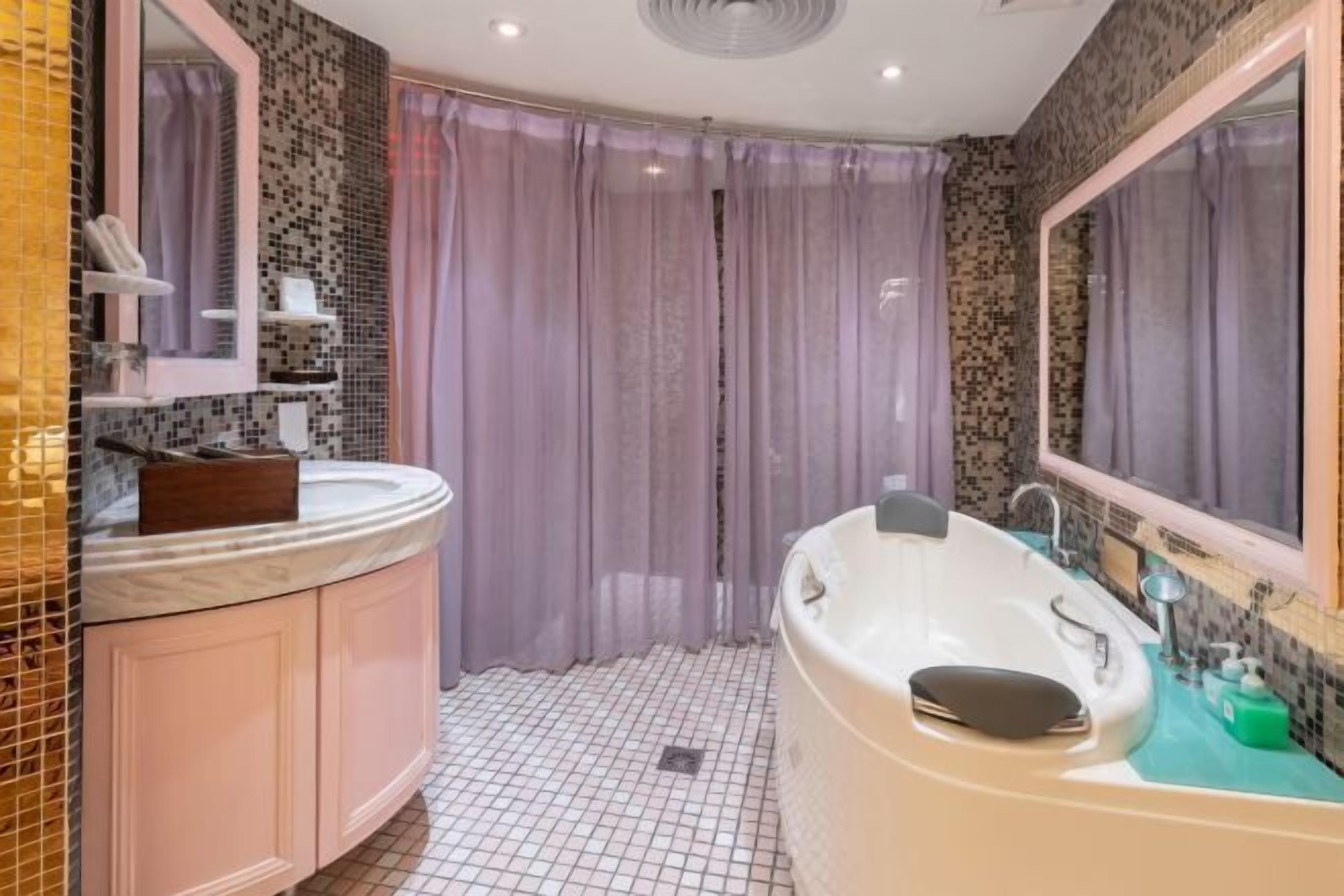 Ein Badezimmer mit einer weißen Badewanne, einem Waschtisch mit Spiegel und einer Duschvorhang.