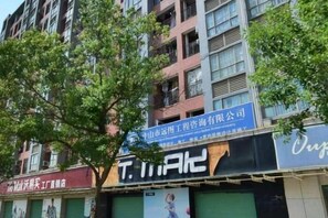 Un edificio de varios pisos con señalización comercial, incluyendo un letrero azul con texto blanco y un letrero negro con texto blanco.