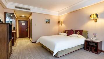 A hotel room with a large bed, a bedside table with a lamp, and a wardrobe.