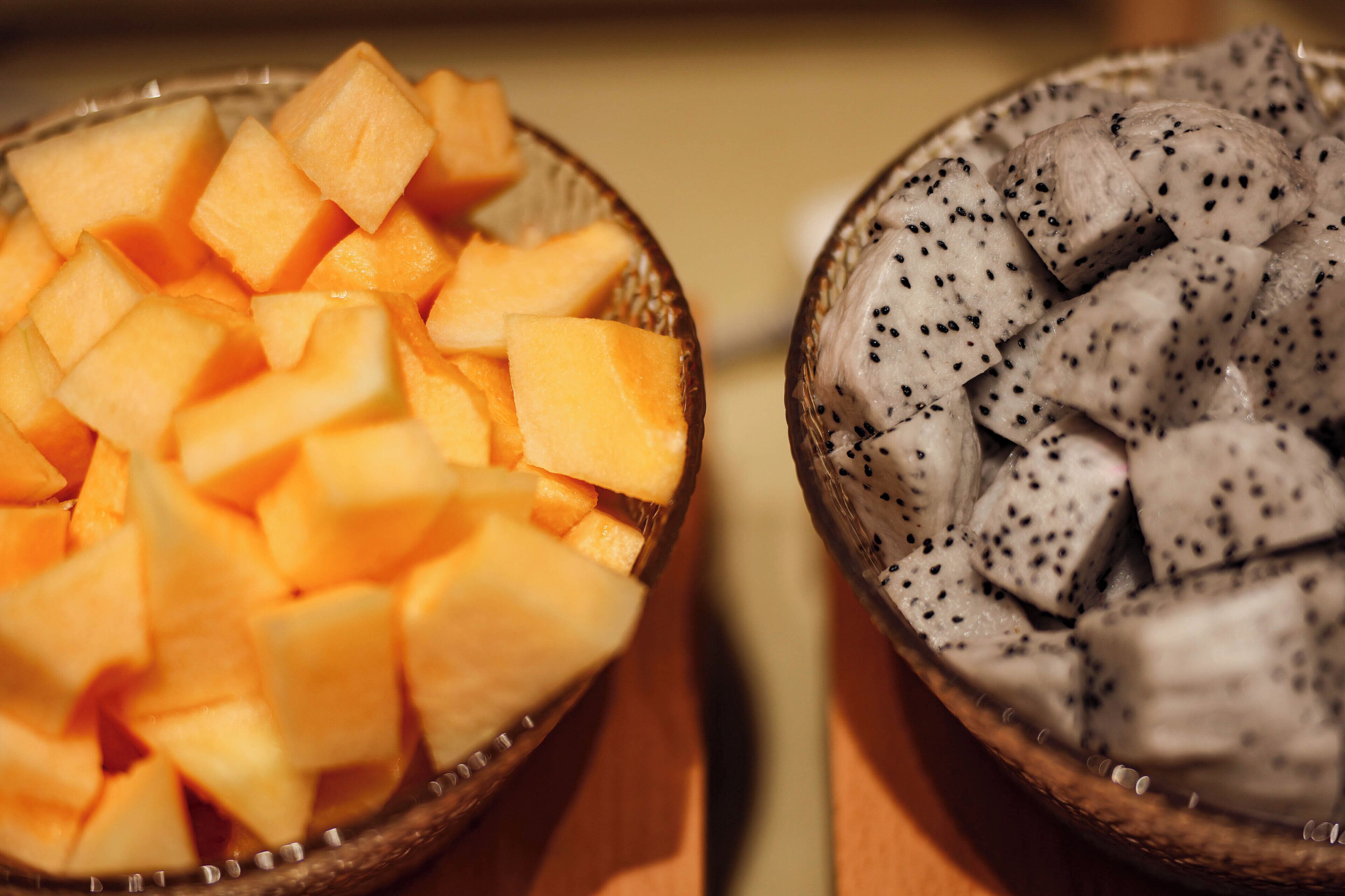 Dos cuencos de fruta, uno con melón en cubos y otro con pitahaya.
