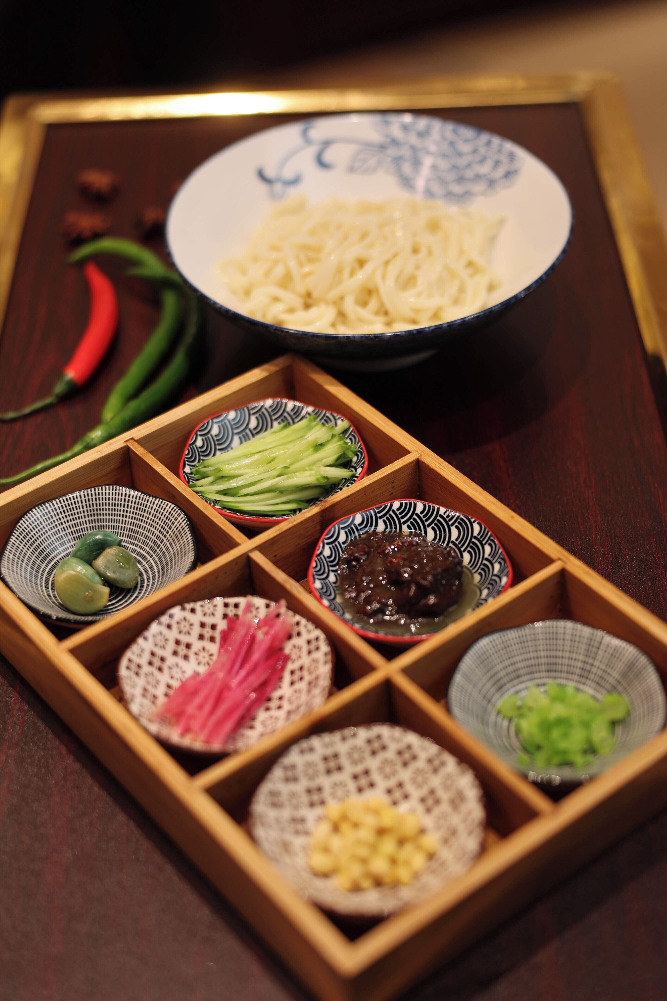 A wooden tray with various bowls containing food items.