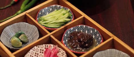 A wooden tray with various bowls containing food items.