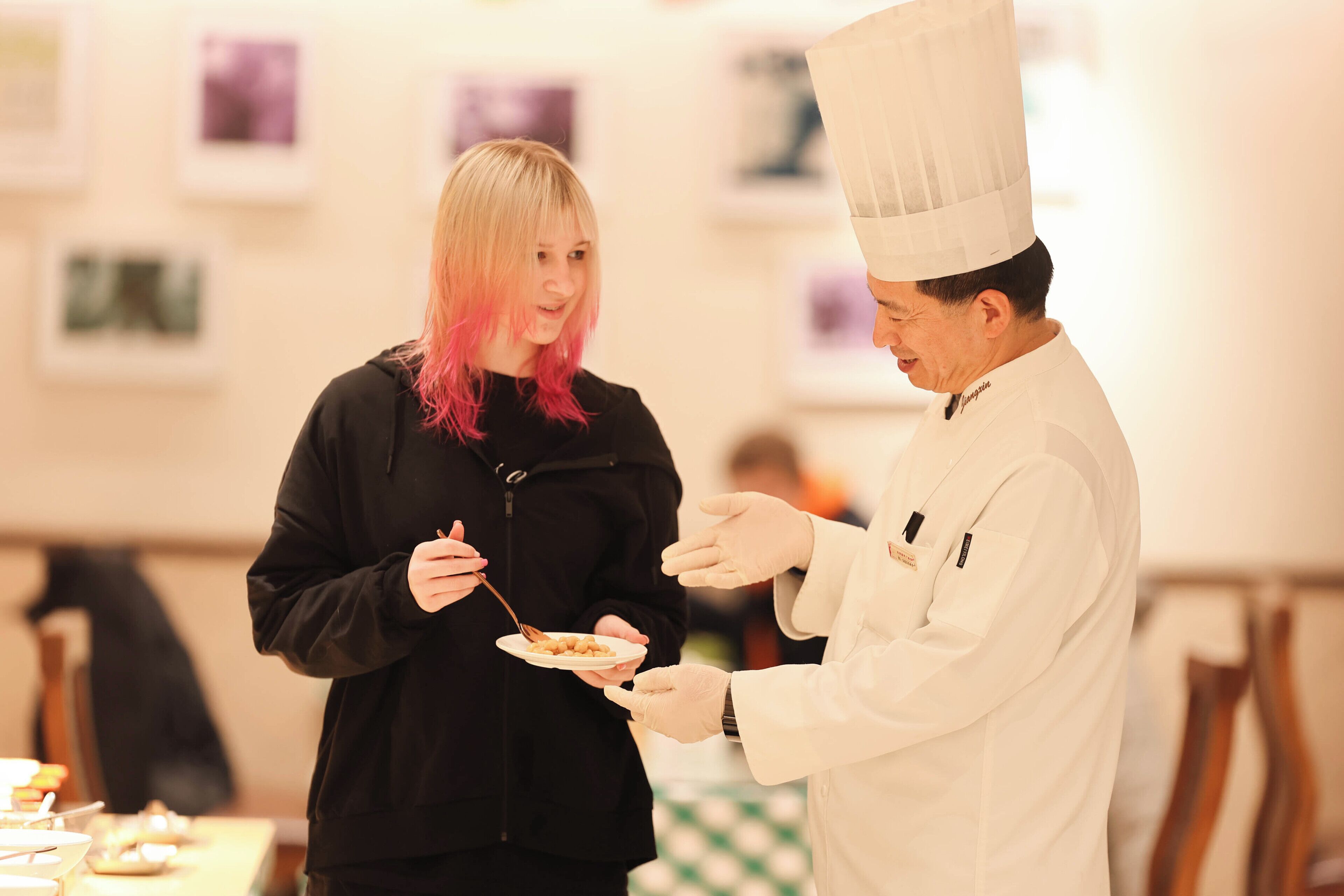 A person in a chef's uniform serving food to another person.