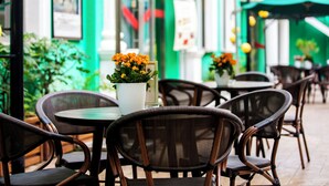 An outdoor cafe with wicker chairs and tables, a green awning, and potted plants with flowers. - Zhongan Hotel Beijing (Beijing)