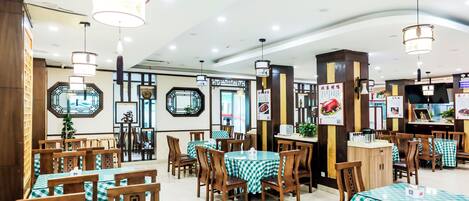 Interior de restaurante com toalhas de mesa xadrez, cadeiras de madeira, luminárias pendentes e decorações nas paredes.