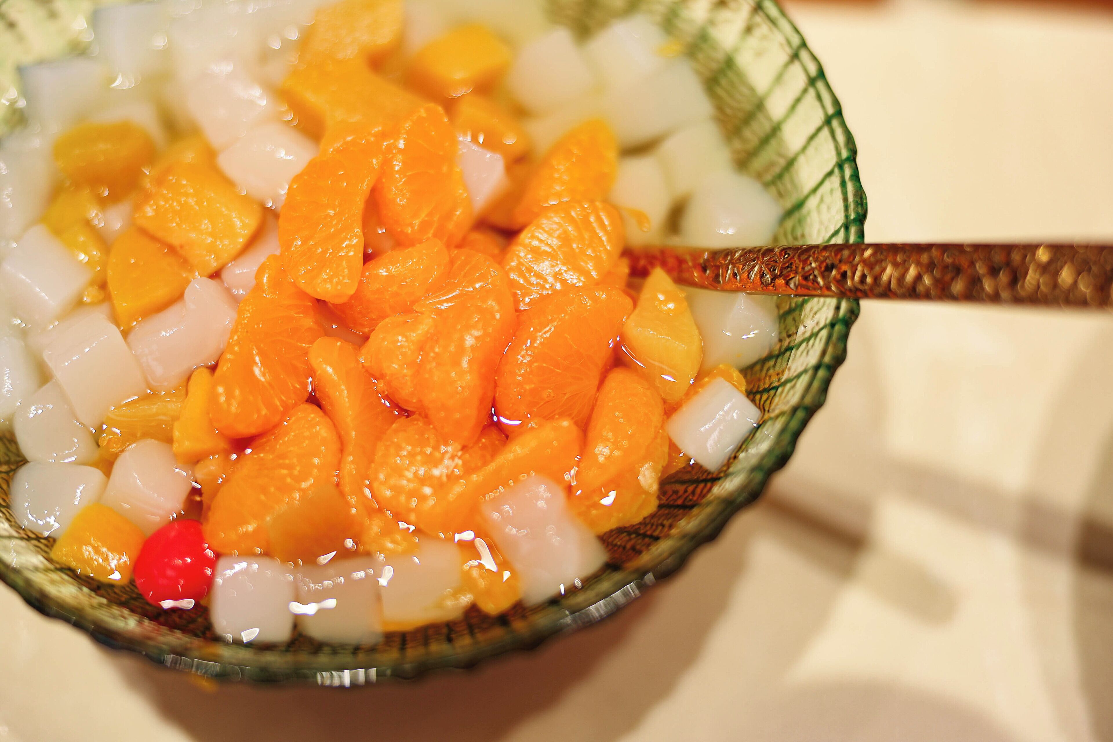 A bowl of fruit salad with a spoon.