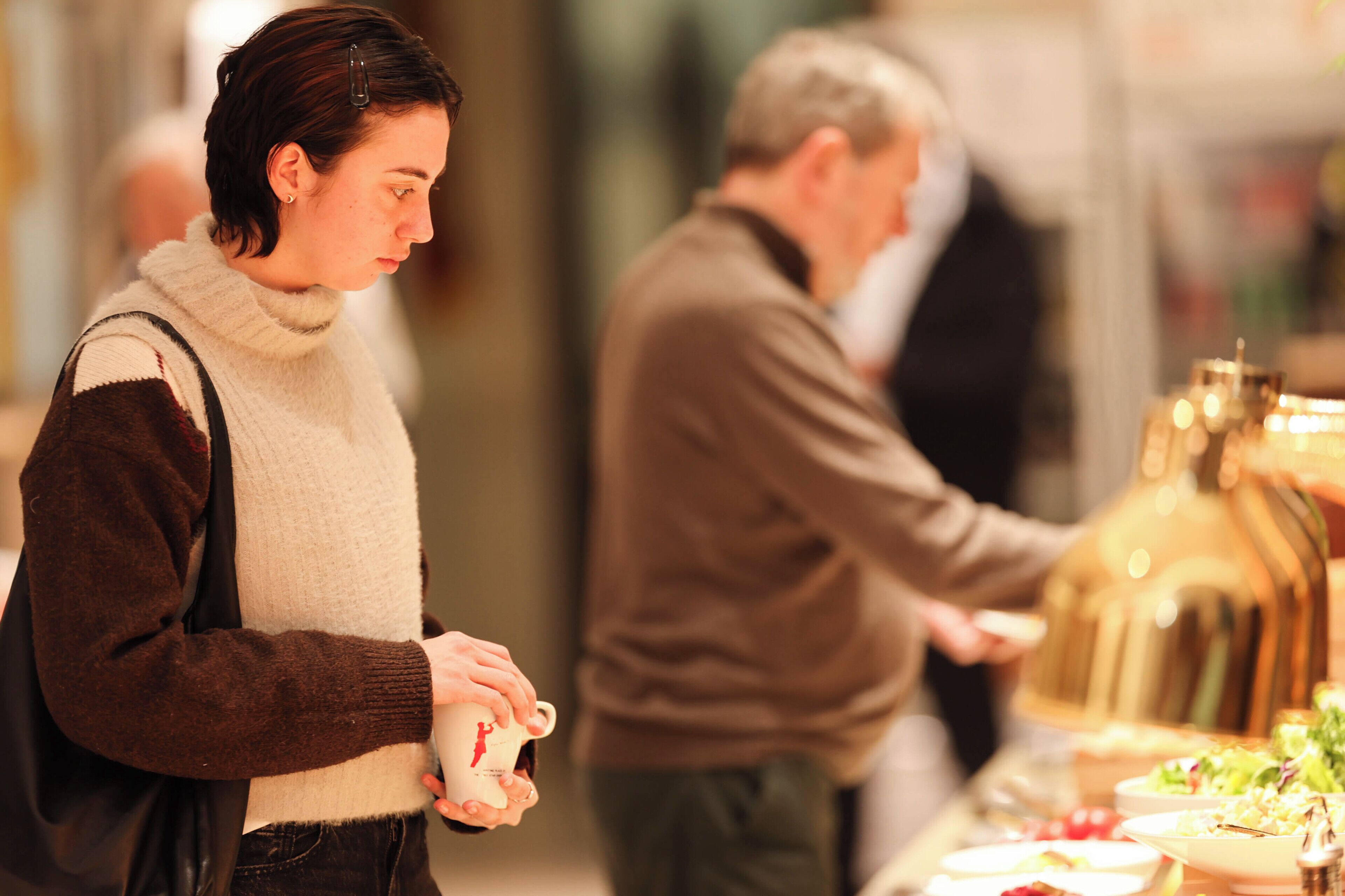 A buffet setup with a variety of dishes and a person serving food.