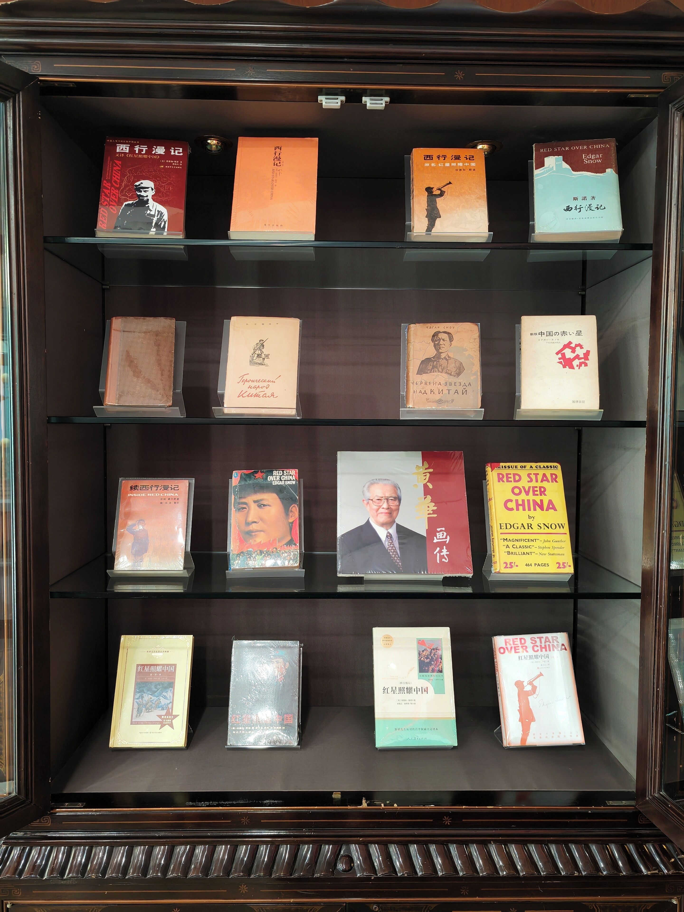 A display case with various books and memorabilia, including a Red Star Over China book and a framed picture.