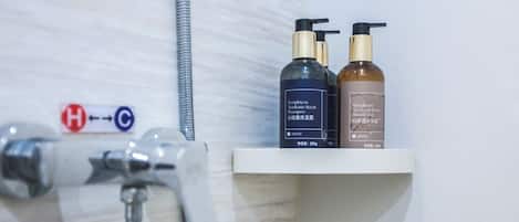 A bathroom with a shower and two bottles of shampoo on a shelf.