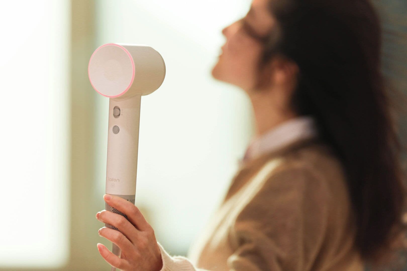 Une personne tenant un appareil doté d’un dessus circulaire et d’un bouton.