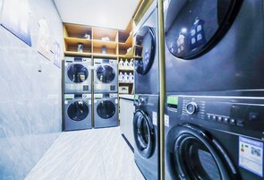 Un cuarto de lavandería con varias lavadoras y estantes llenos de botellas de detergente.