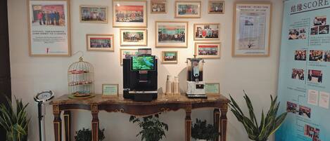 Un espace d’accueil agrémenté de photos encadrées au mur, d’un coin café et d’un écran numérique.