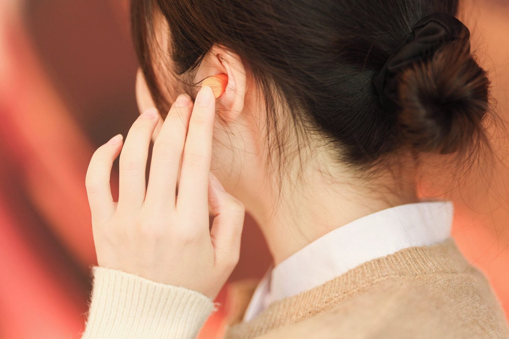 A person with a bun hairstyle wearing a sweater.