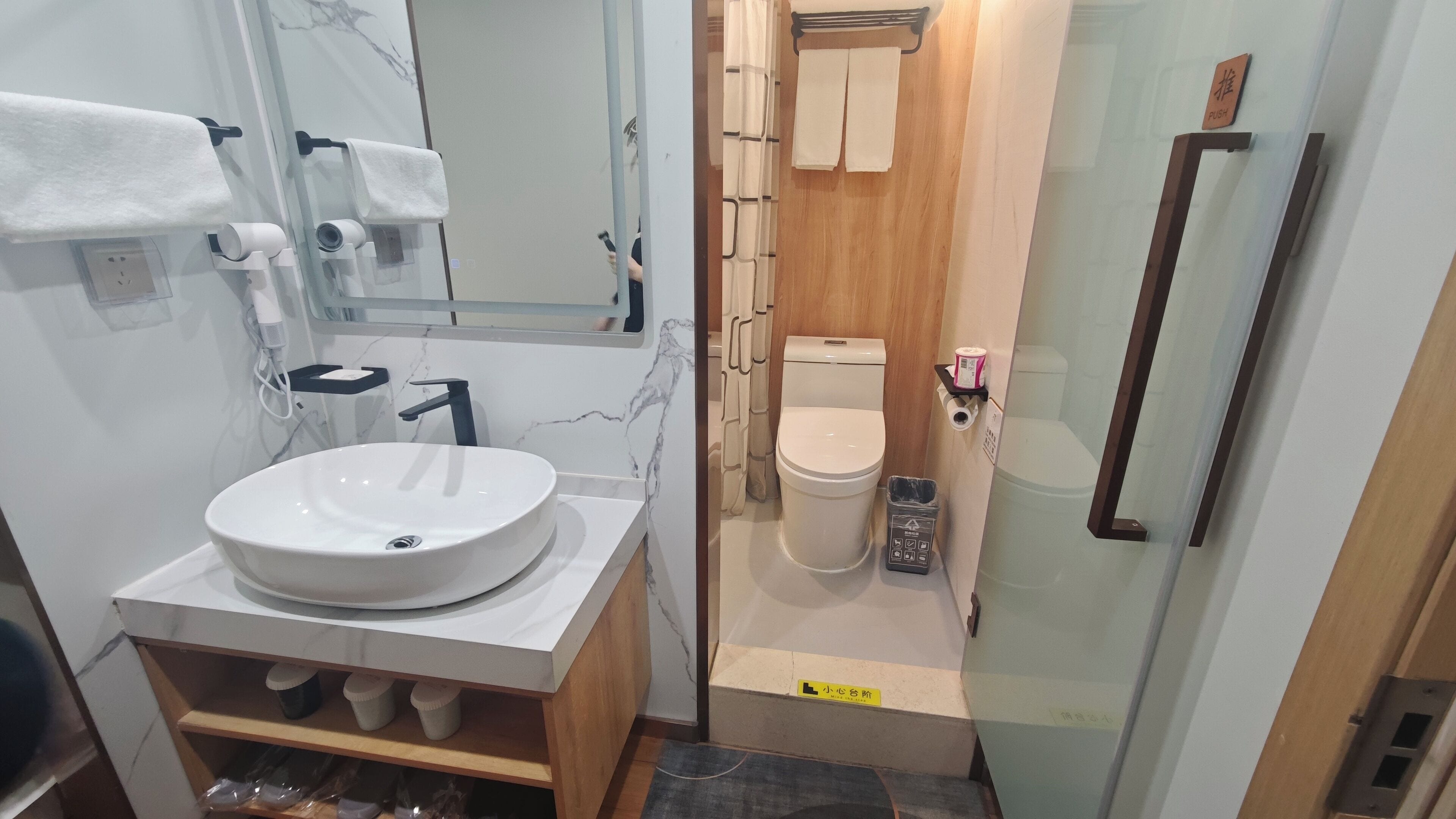 Un baño pequeño con un lavabo redondo, inodoro y cabina de ducha de vidrio.