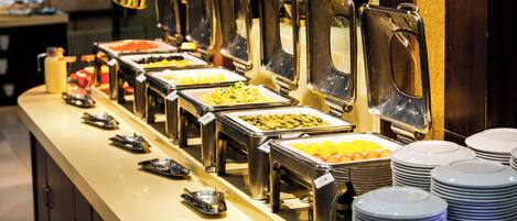 A buffet line with various food stations, including fruits, vegetables, and other dishes.