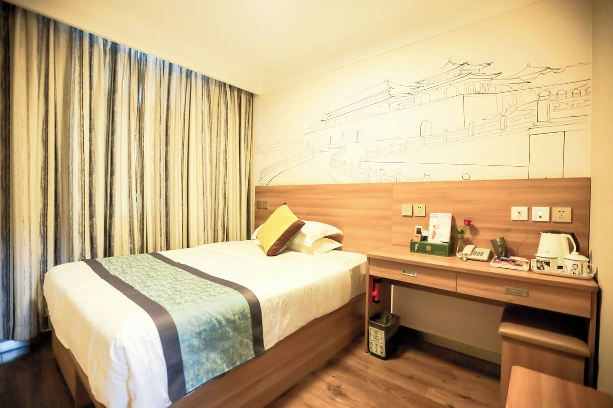 Habitación de hotel con cama, escritorio y un mural en la pared.