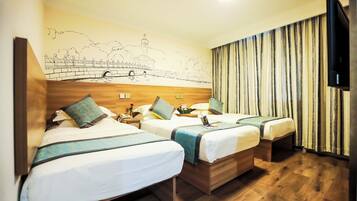 Habitación de hotel con tres camas, cabeceros de madera, un mural de un puente y un televisor a la derecha.