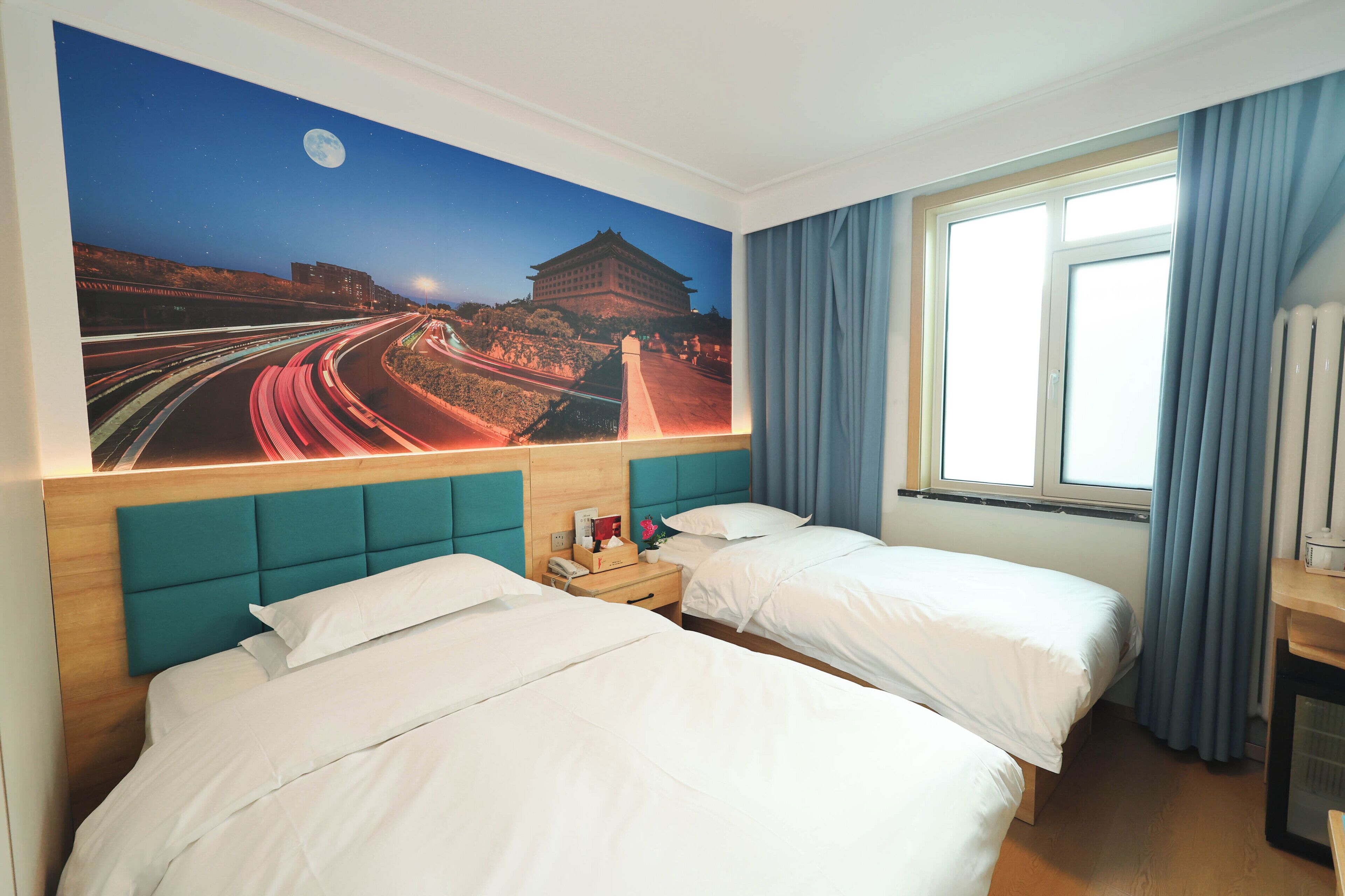 Habitación de hotel con dos camas, un mural del cielo nocturno, una ventana con cortinas y un radiador.