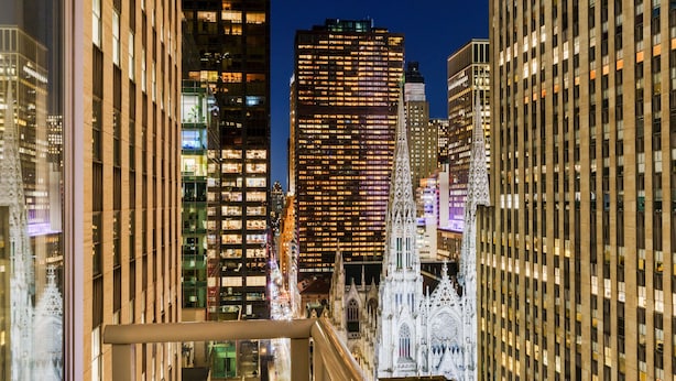 A nighttime cityscape with modern high-rise buildings and a historic cathedral with intricate architecture.