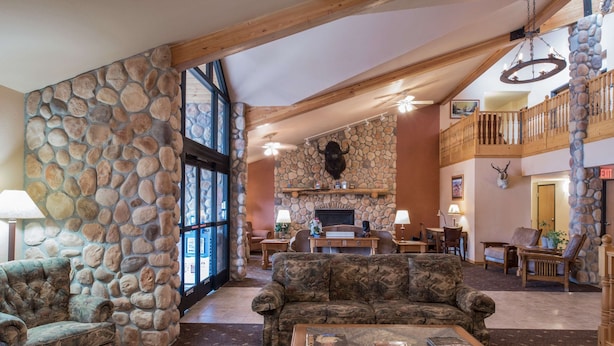 Un hall d’entrée spacieux avec des murs en pierre, une cheminée et un plafond haut orné de poutres en bois.
