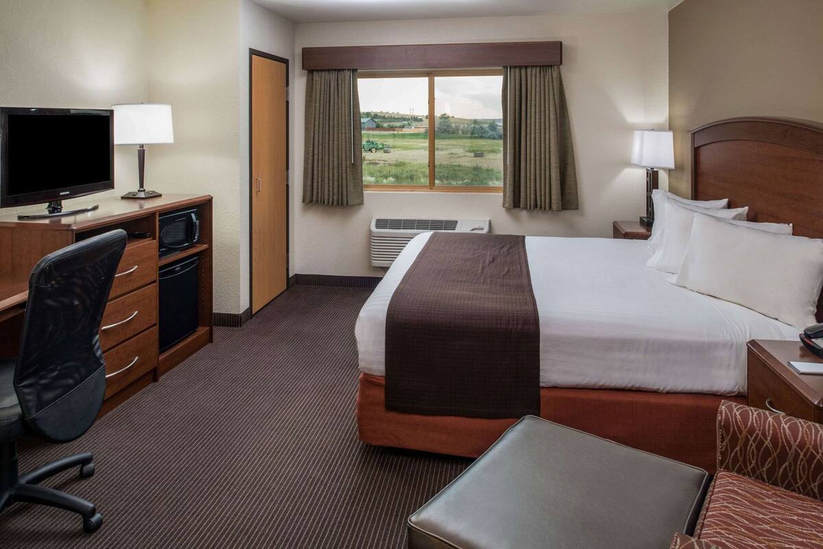 Une chambre d’hôtel équipée d’un lit, d’un bureau, d’une chaise, d’une télévision et offrant une vue sur l’extérieur.