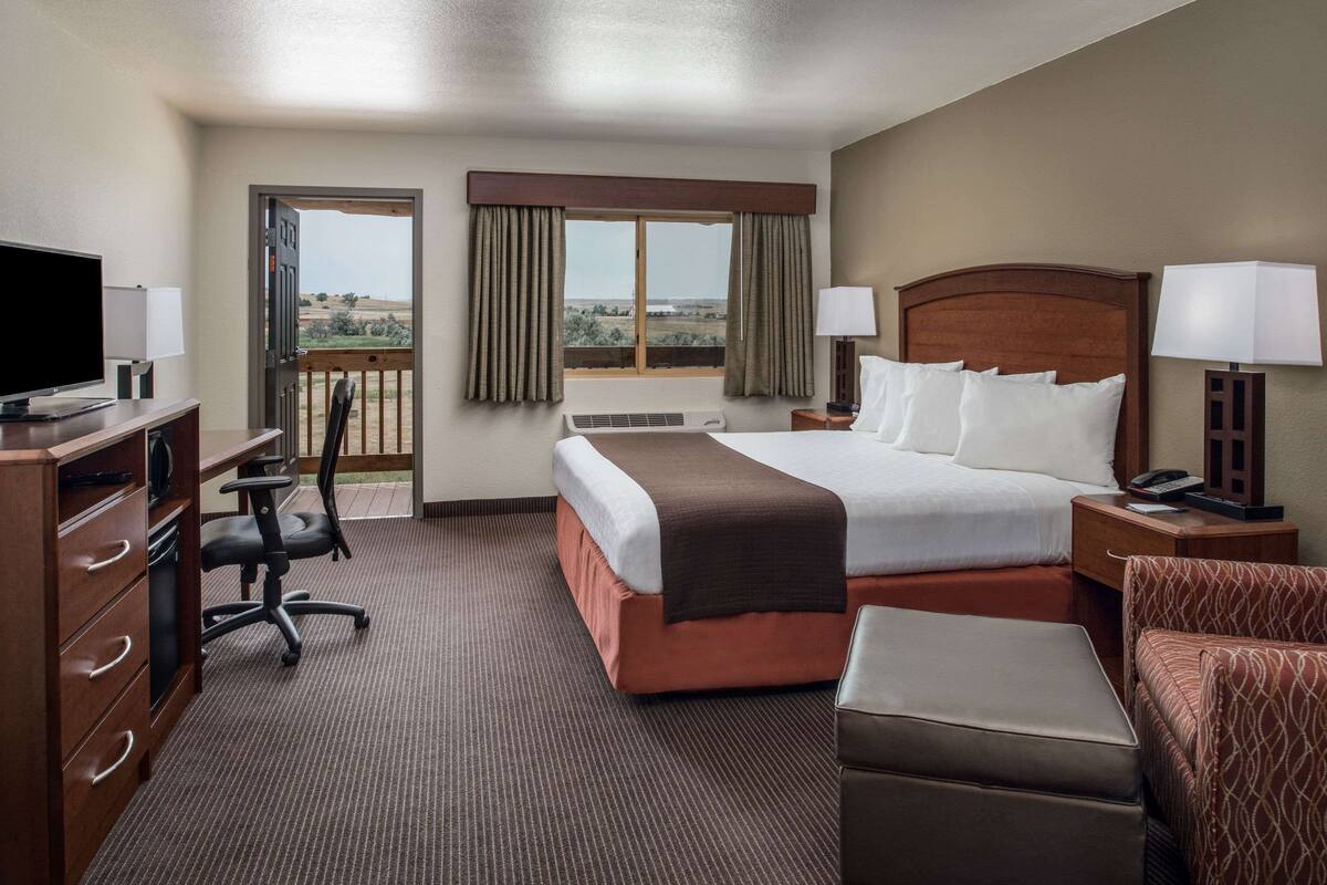 Une chambre d’hôtel équipée d’un lit, d’un bureau, d’une chaise et offrant une vue sur l’extérieur.