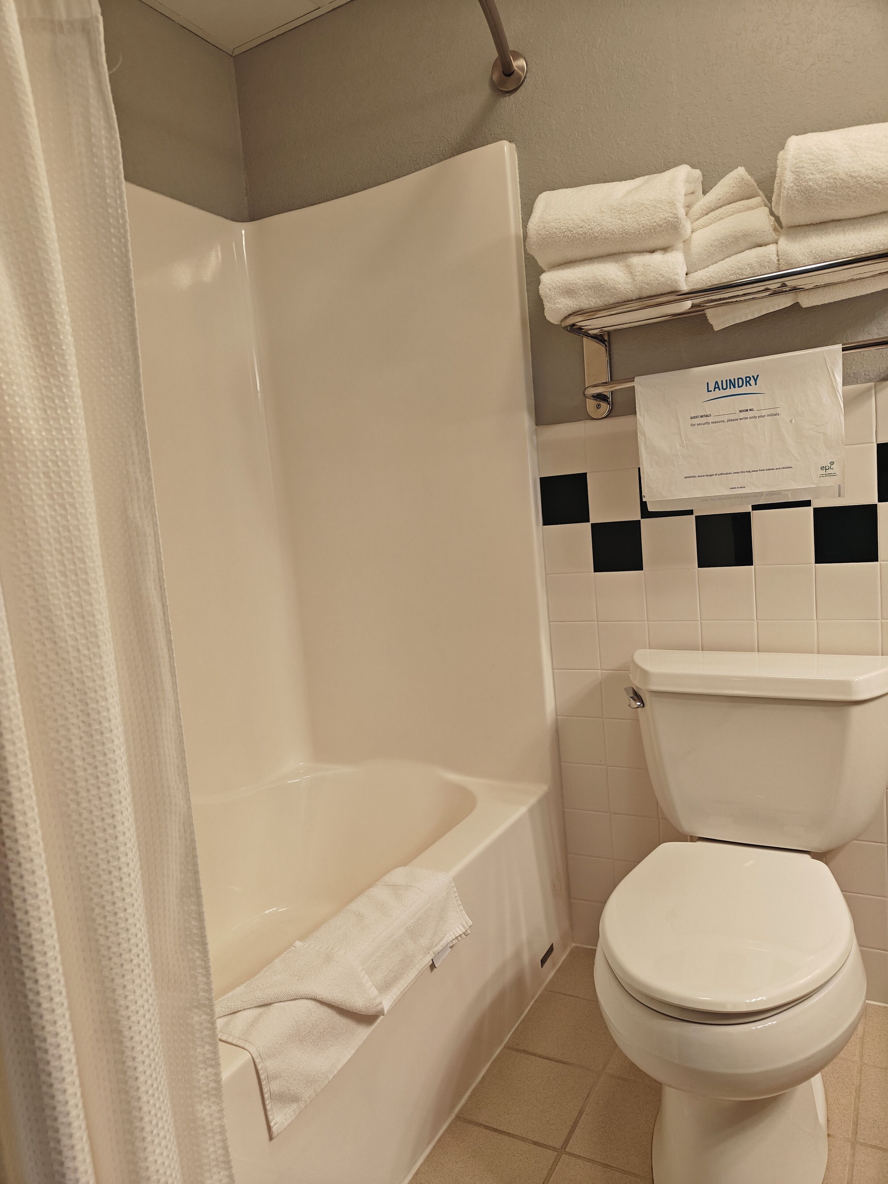 Une salle de bain équipée d’une baignoire, de toilettes et d’un porte-serviettes avec des serviettes pliées.