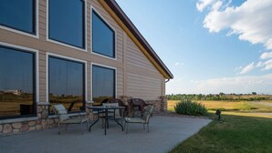 Une maison dotée de grandes fenêtres, d’un espace extérieur aménagé et de fondations en pierre.