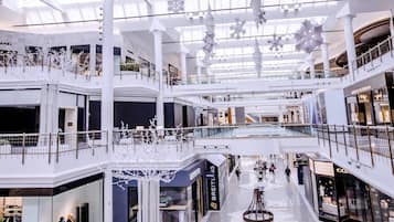 A multi-level shopping mall with a high ceiling, glass panels, and modern lighting fixtures.