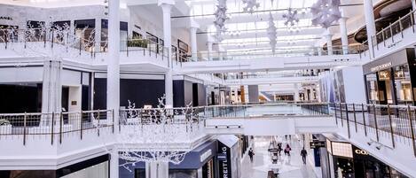 A multi-level shopping mall with a high ceiling, glass panels, and modern lighting fixtures.