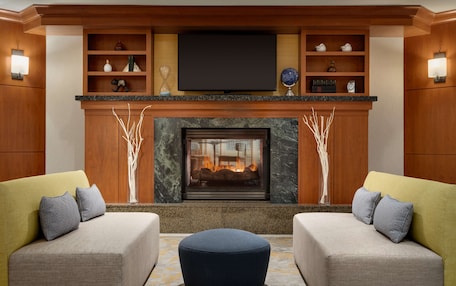 A modern living room with a fireplace, two sofas, and a television above the fireplace.