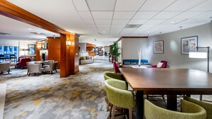 En rymlig hotellobby med en stor receptionsdisk i trä, bekväma sittgrupper och en modern mattdesign.