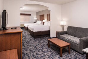 A hotel room with a bed, a sofa, a desk, and a television.