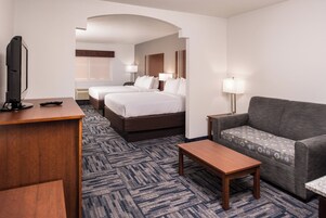 Una habitación de hotel con cama, sofá, escritorio y televisión.