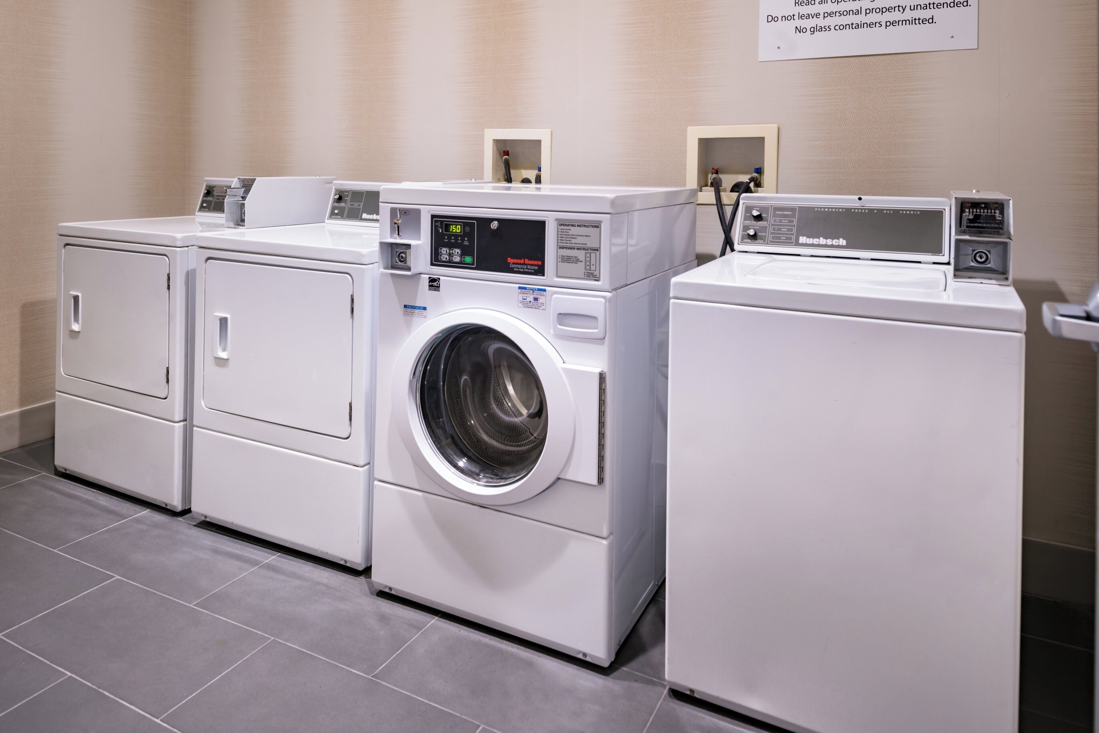 Une rangée de trois lave-linge industriels blancs dans un établissement.