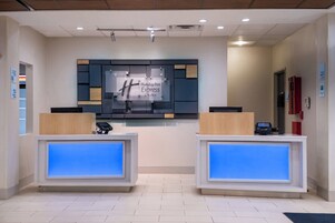 Una recepción con una pantalla digital, un letrero de Holiday Inn Express & Suites, y un extintor en la pared.