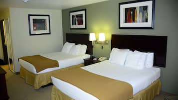 A hotel room with two beds, a nightstand, a telephone, and framed pictures on the wall.