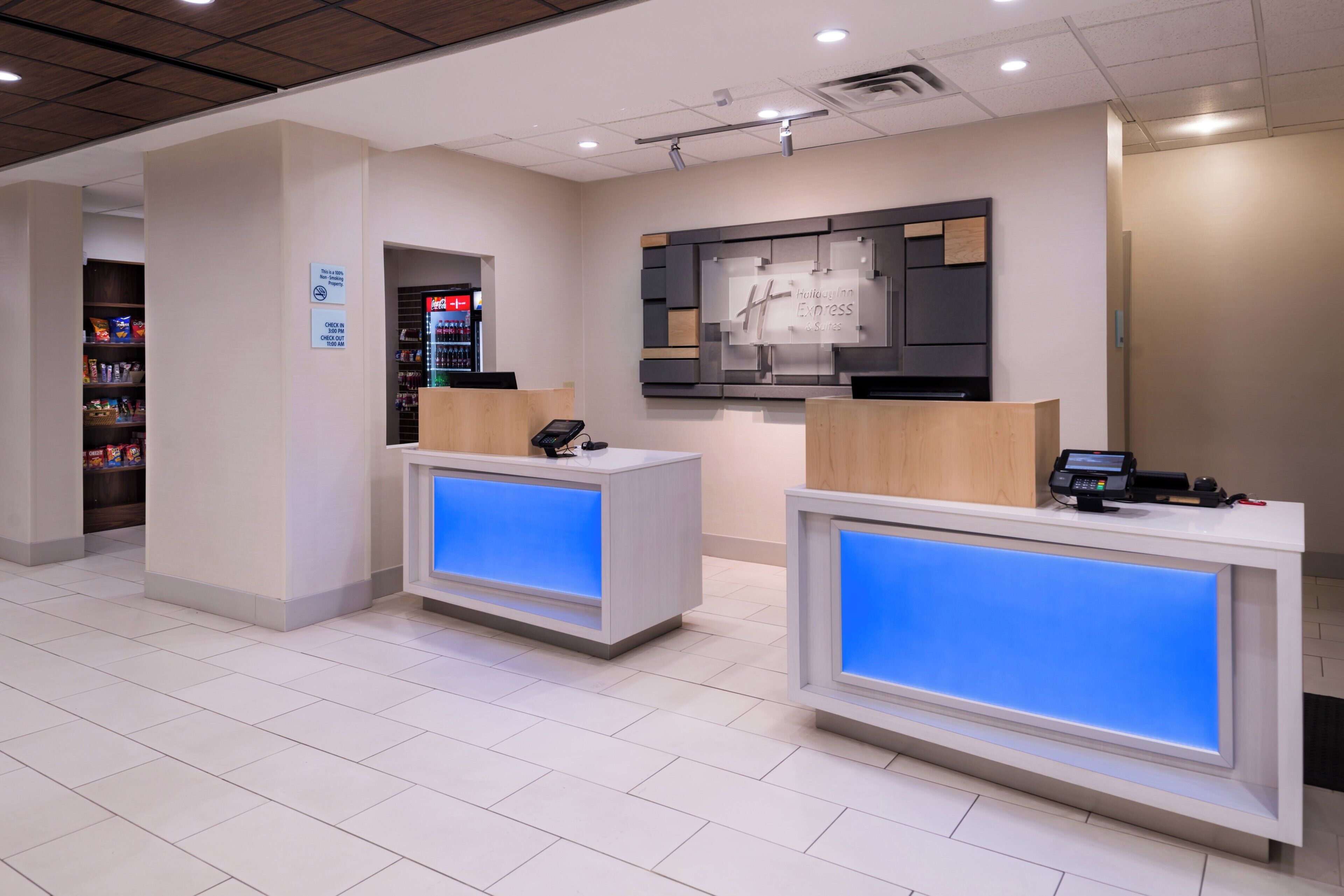 A hotel reception area with two reception desks, a vending machine, and a wall-mounted sign.