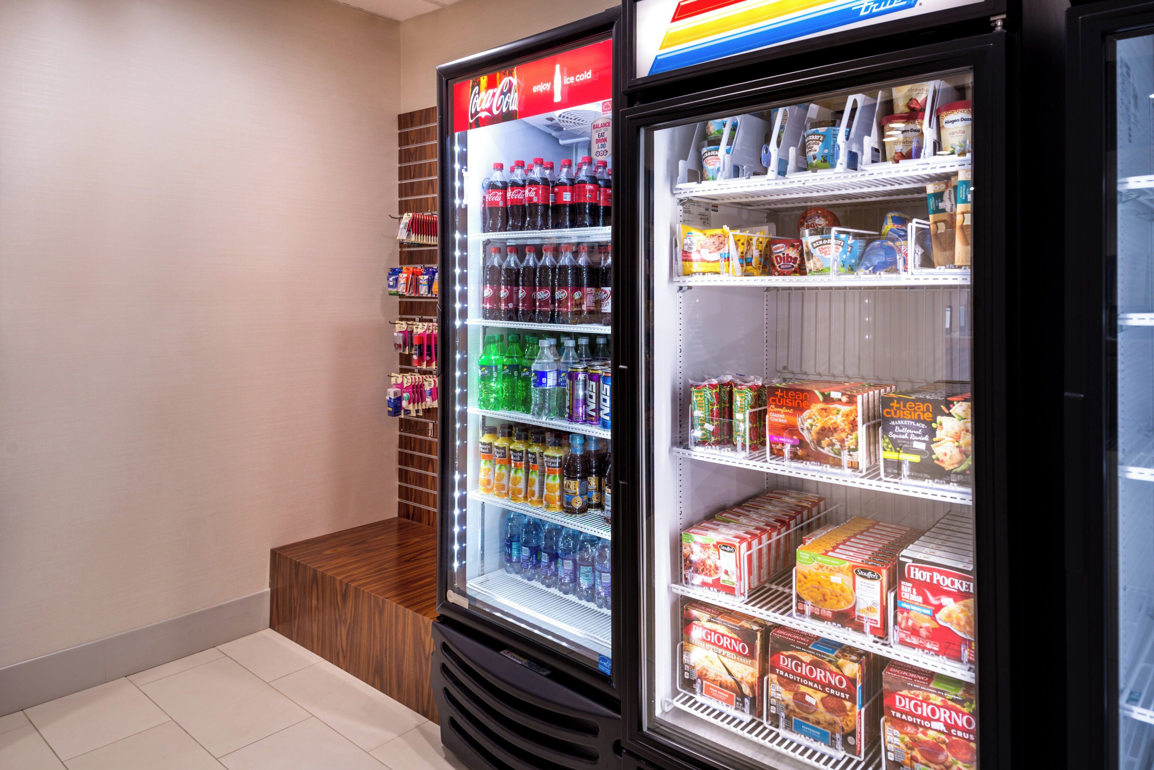 A vending machine with various beverages and snacks, and a refrigerated display case with frozen food items.