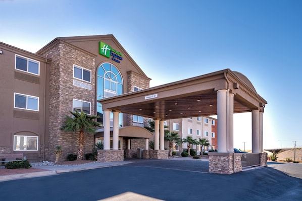 A hotel with a covered entrance, stone facade, and a clear sky.