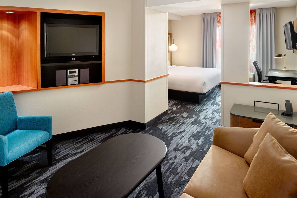 A hotel room with a bed, a TV, a desk, a chair, and a sofa.