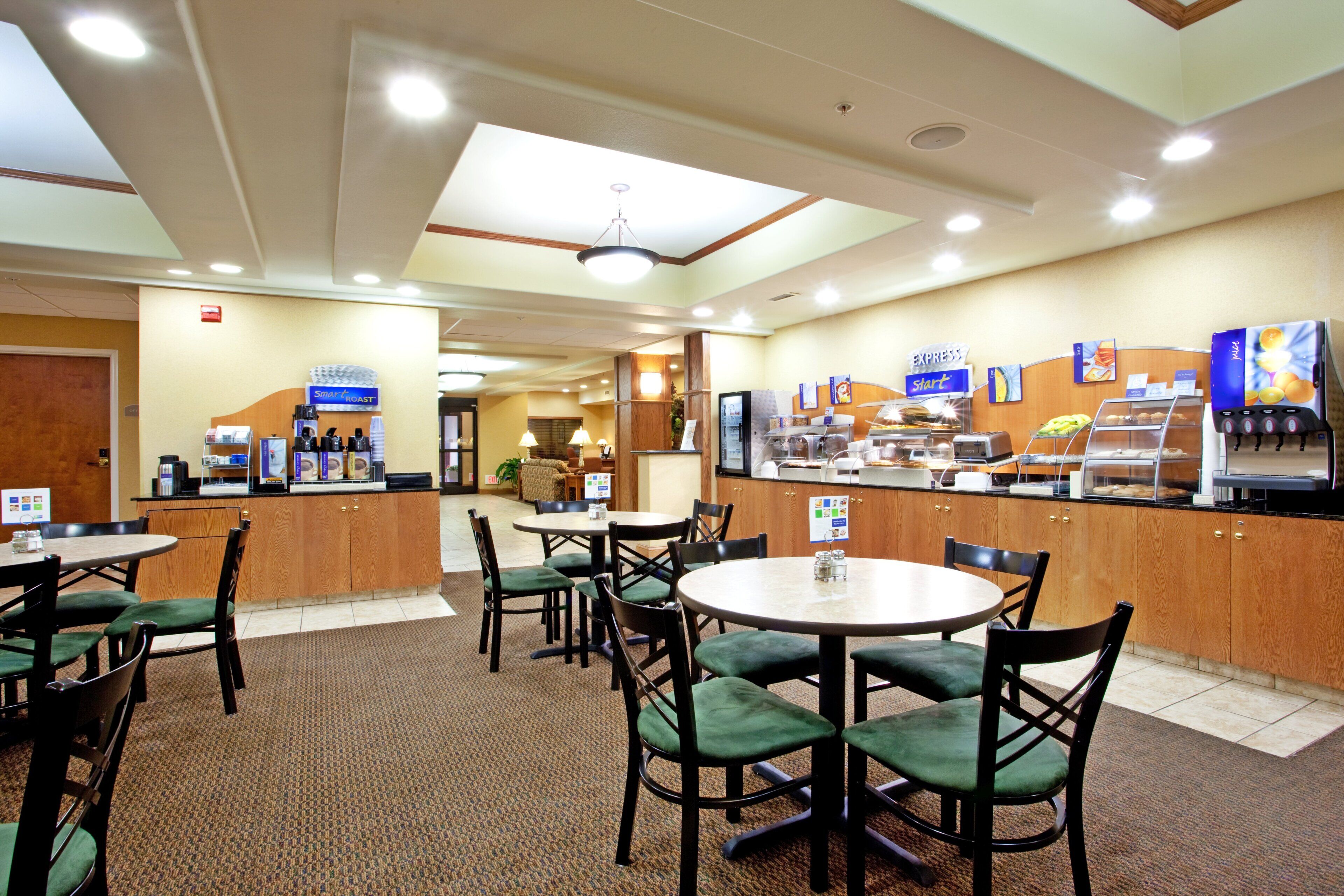 Ein Hotel-Essbereich mit mehreren Tischen und Stühlen, einer Kaffeebar und einer Rezeption.