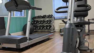 Un gimnasio con equipamiento cardiovascular, pesas y una cinta de correr.