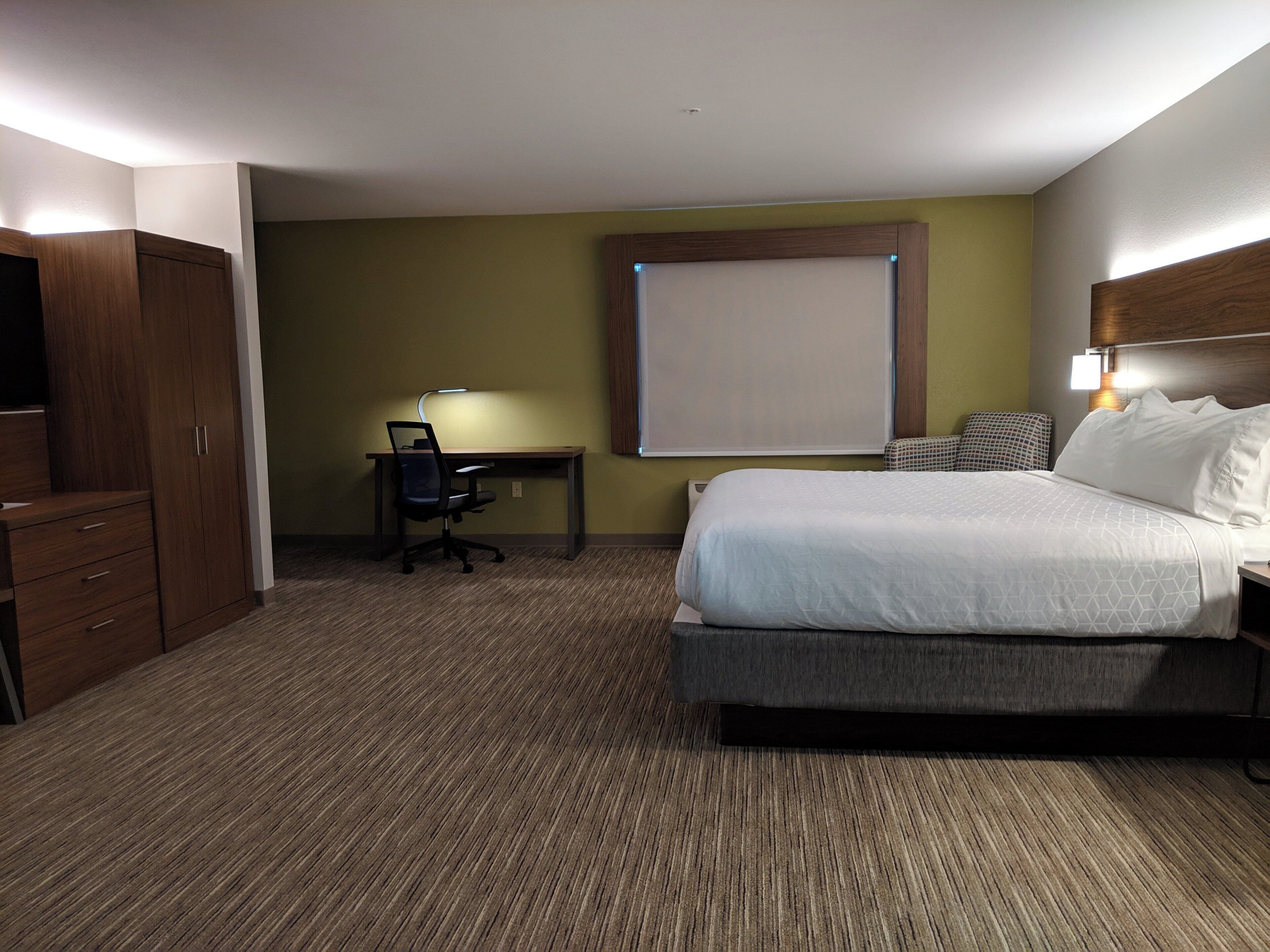 Habitación de hotel con cama, escritorio, silla y armario.
