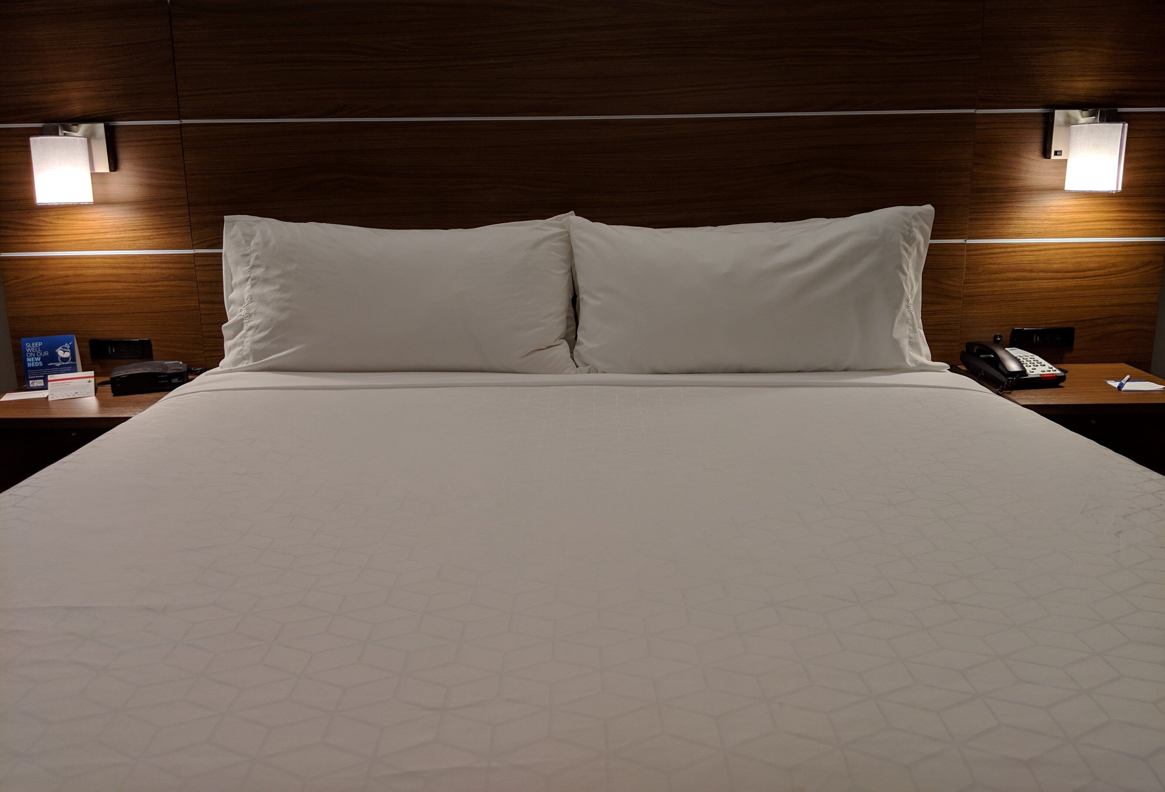 Habitación de hotel con una cama grande, dos mesitas de noche y un teléfono en la pared.