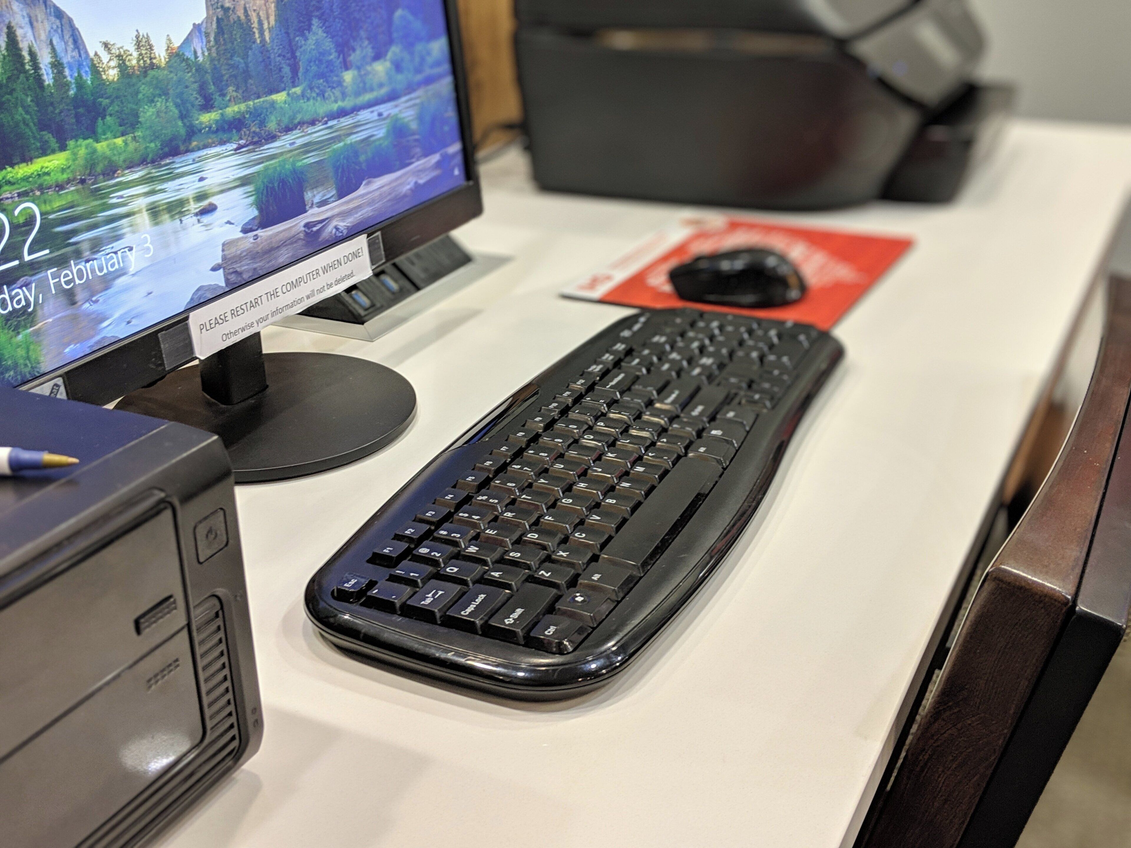 Een bureau met een toetsenbord, een monitor waarop een panoramisch achtergrondbeeld staat en een printer.