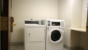 A compact, two-door laundry room with a front-loading washer and dryer.