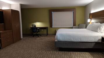 Een hotelkamer met een bed, bureau, stoel en kledingkast.